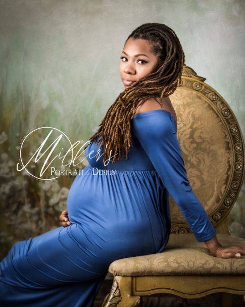 Maternity portrait on golden chair in front of green meadow backdrop