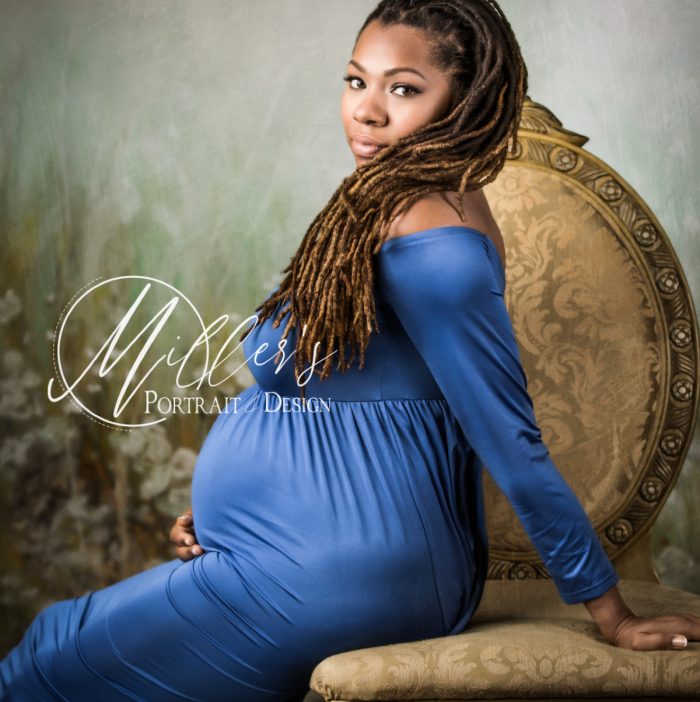 Maternity portrait on golden chair in front of green meadow backdrop