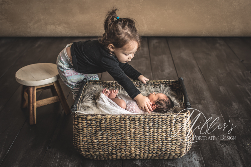 Portrait of Newborn with Big Sister in Wicker Basket